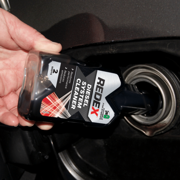 Pouring Redex diesel injector cleaner into a car fuel tank, showing how to use redex diesel treatment before refuelling with diesel