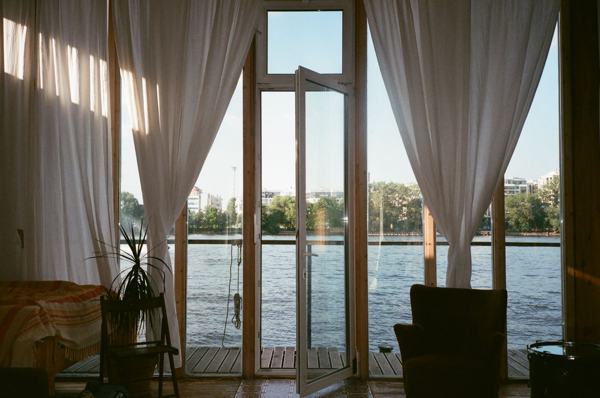 White-framed glass doors and windows with warm wood flooring in a cosy neutral room