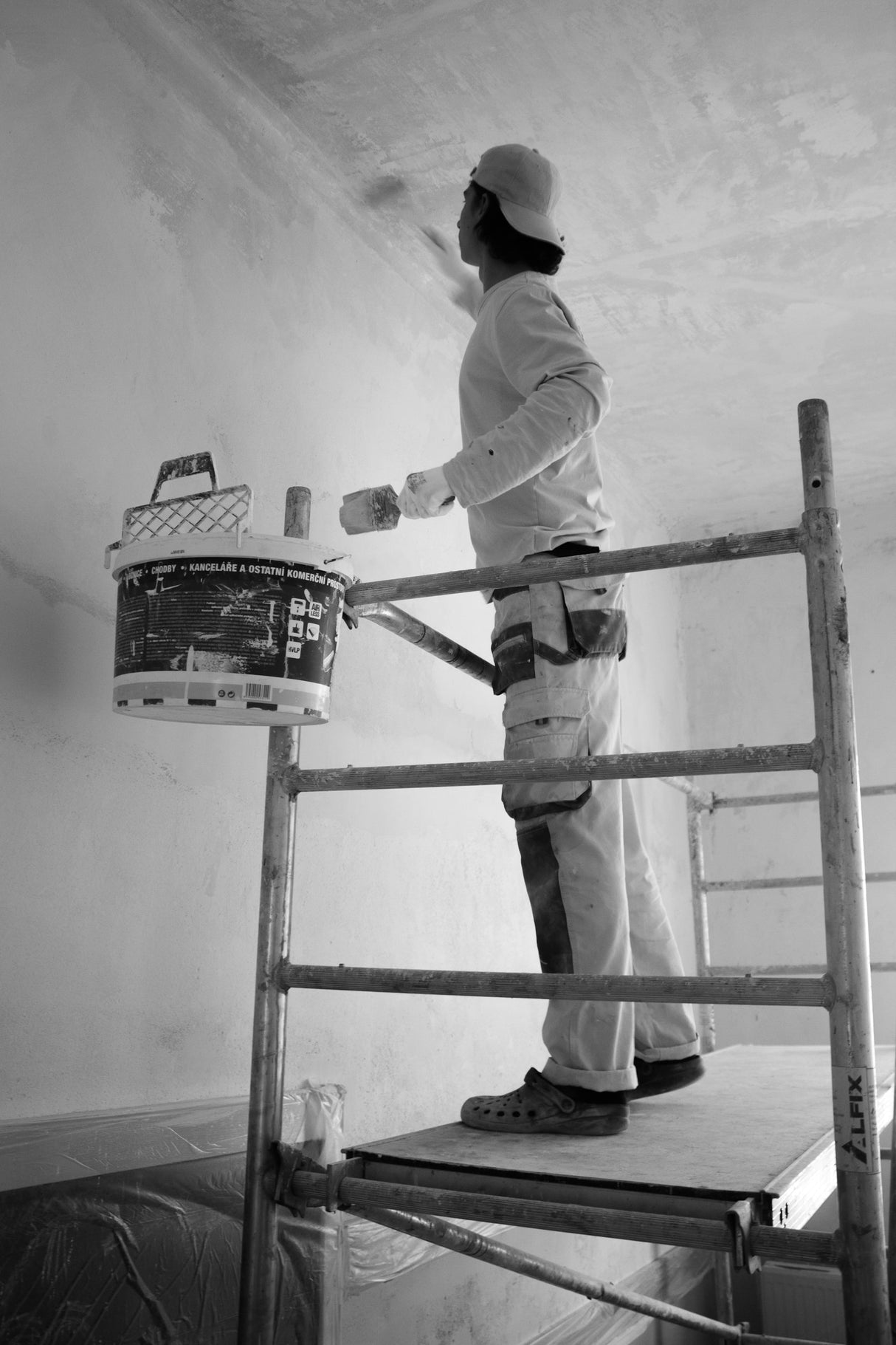 Decorator rolling paint across a large wall area with a wide roller