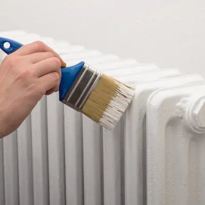 Radiator being painted with a brush, close up of white enamel finish