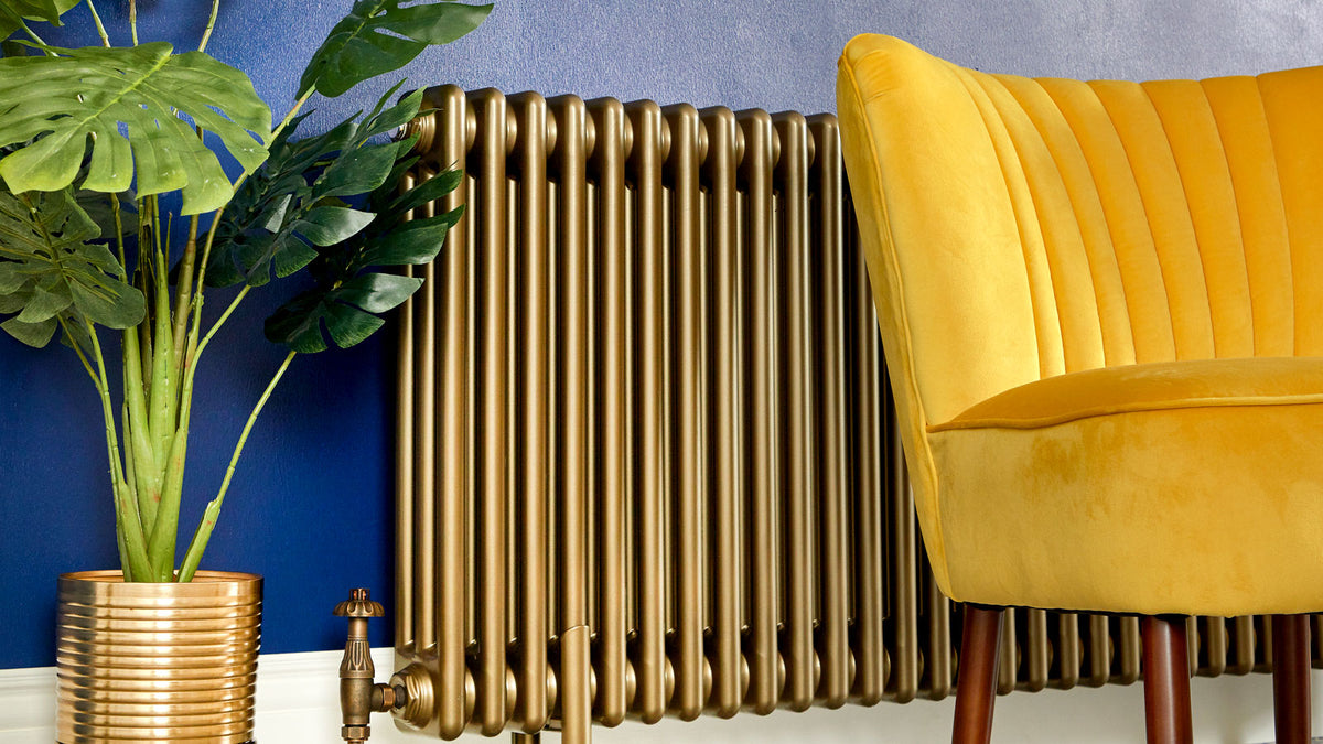 Column radiator painted gold against a dark blue wall in a living room