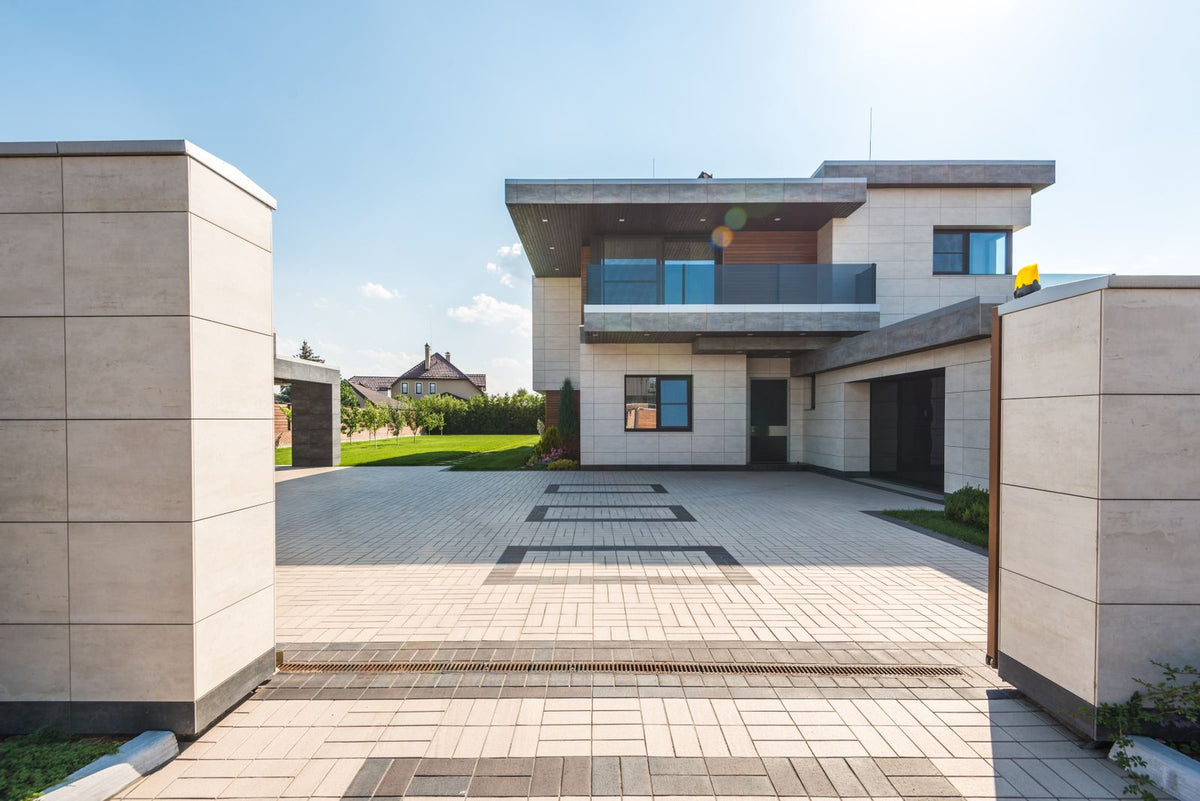 Modern minimalist home with a spacious light grey porcelain-style paved driveway and garden