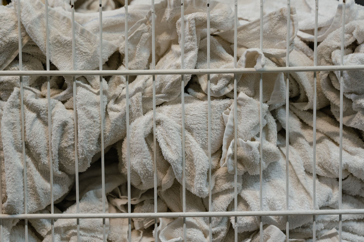 Stack of clean white towels folded neatly inside a wicker laundry basket