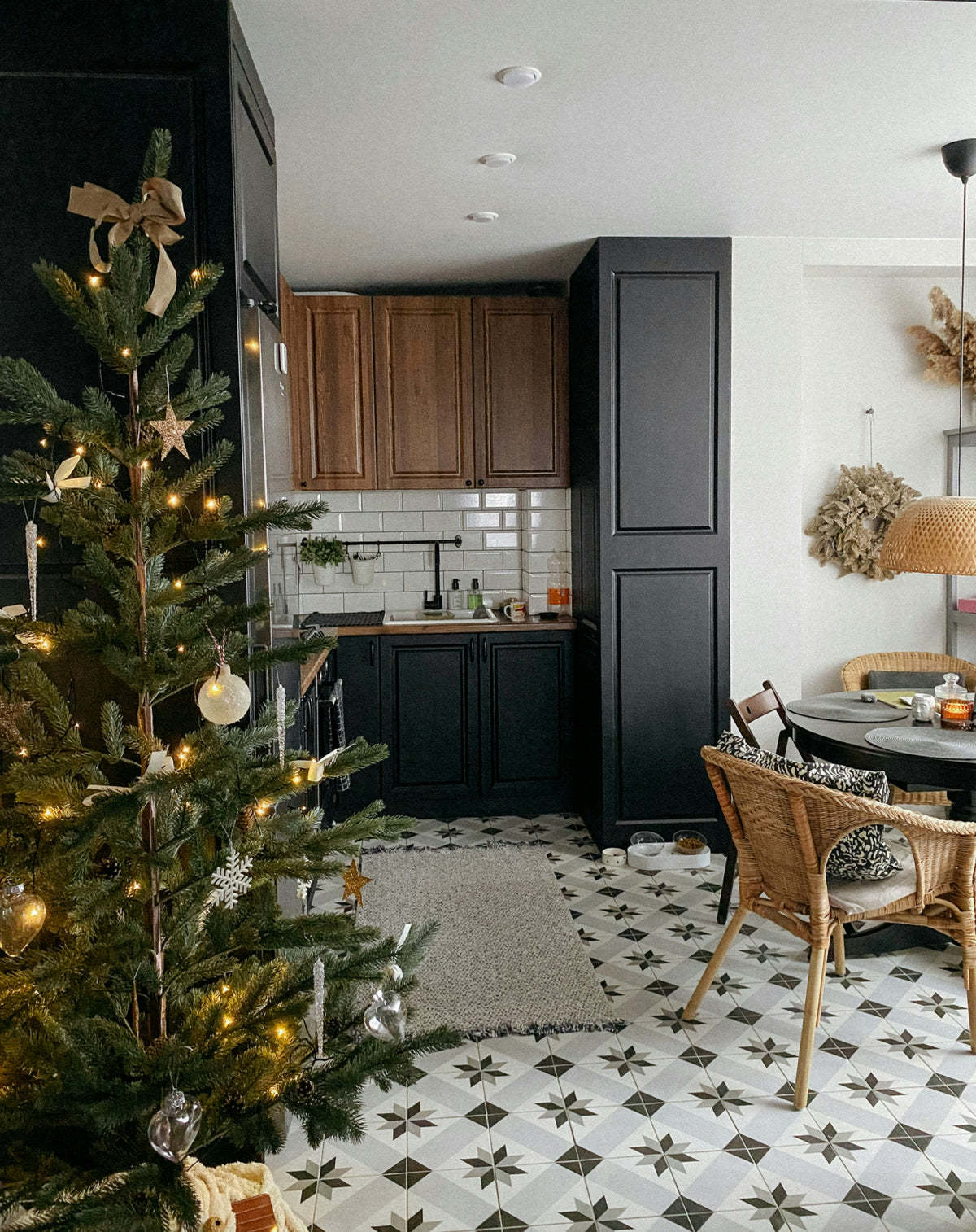 A decorated Christmas tree standing beside a dining table in an open-plan festive kitchen