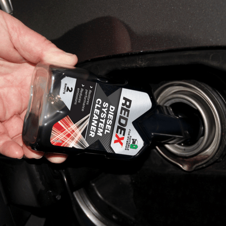 Pouring Redex diesel injector cleaner into a car fuel tank, showing how to use redex diesel treatment before refuelling with diesel