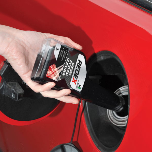 Pouring Redex diesel injector cleaner into a car fuel tank, showing how to use redex diesel treatment before refuelling with diesel