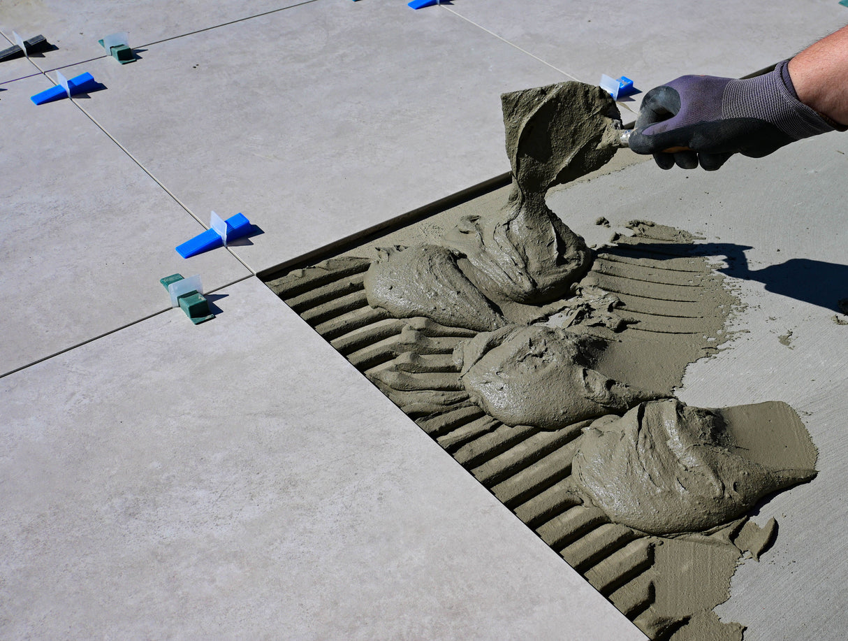Gloved hand brushing jointing compound firmly into the gaps between outdoor paving slabs