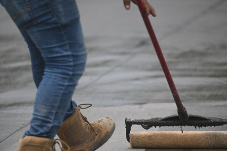 Applying paving sealer with a roller to a patio surface