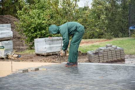 Tradesperson laying a paving slab during patio installation
