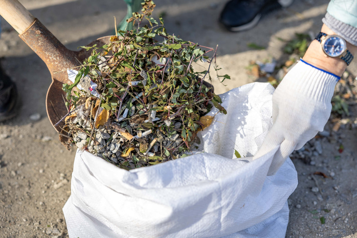 Filling a reusable woven rubble sack with garden waste