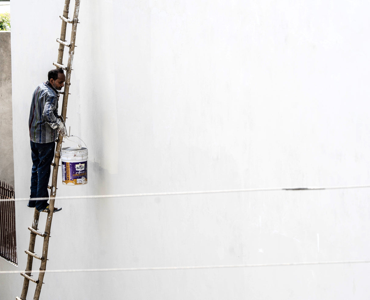 Painter on a ladder repainting an exterior wall during renovation