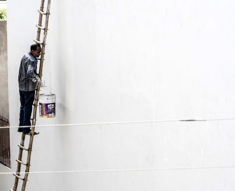 Painter on a ladder repainting an exterior wall during renovation