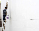 Painter on a ladder repainting an exterior wall during renovation