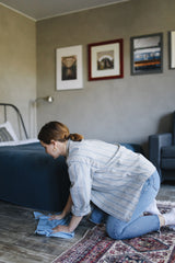 Person wiping a carpet with a cloth after applying carpet cleaning mousse