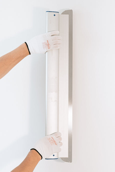 Gloved hand smoothing joint compound flat with a filling knife blade