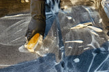 Gloved hand using a stiff brush to work carpet shampoo into carpet fibres