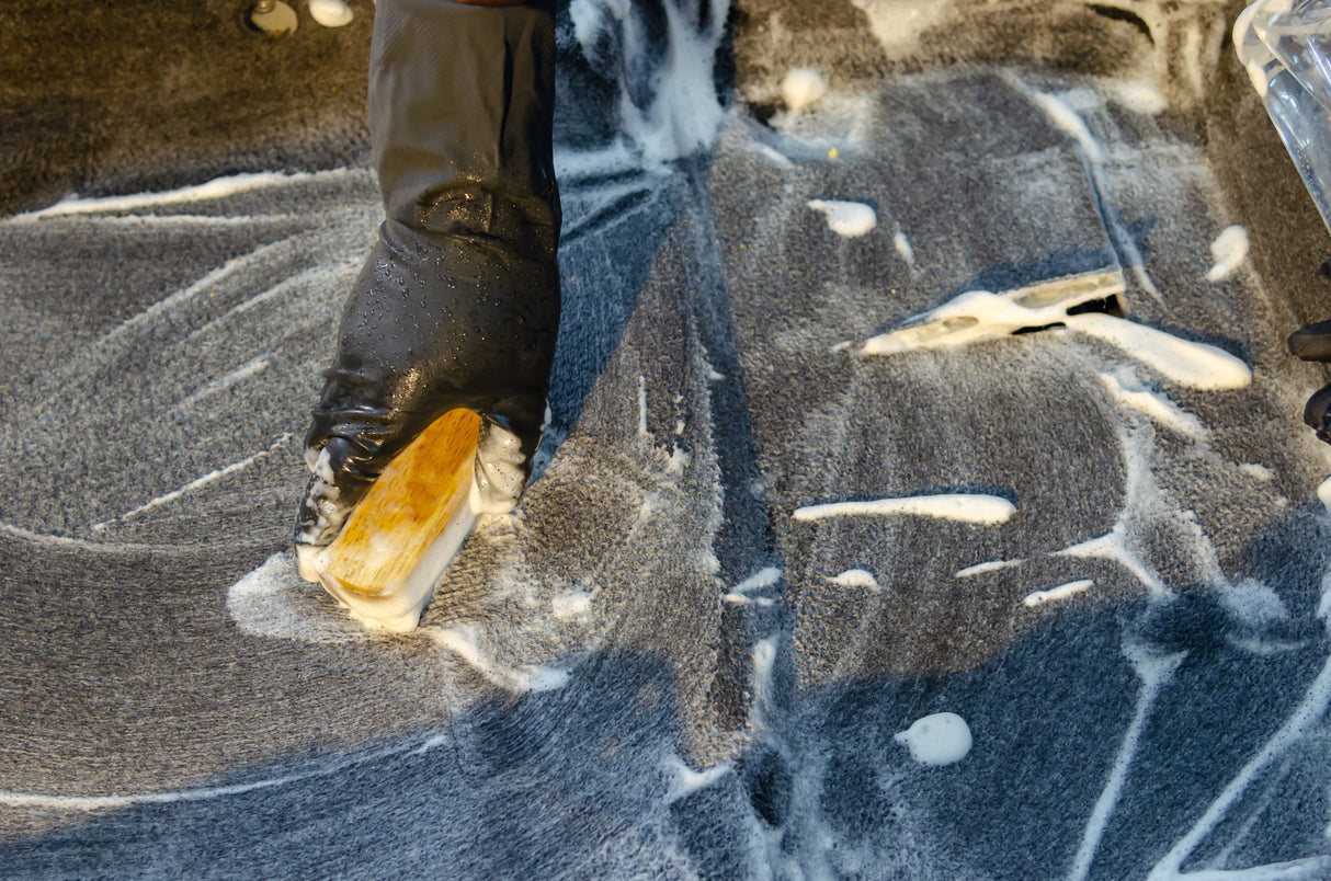 Close up of a carpet being scrubbed with soap suds to lift a stubborn stain