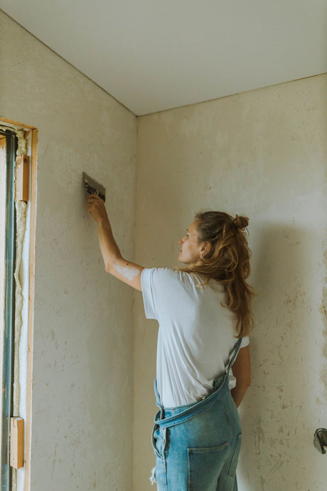 Decorator applying joint compound over a wide plasterboard seam indoors