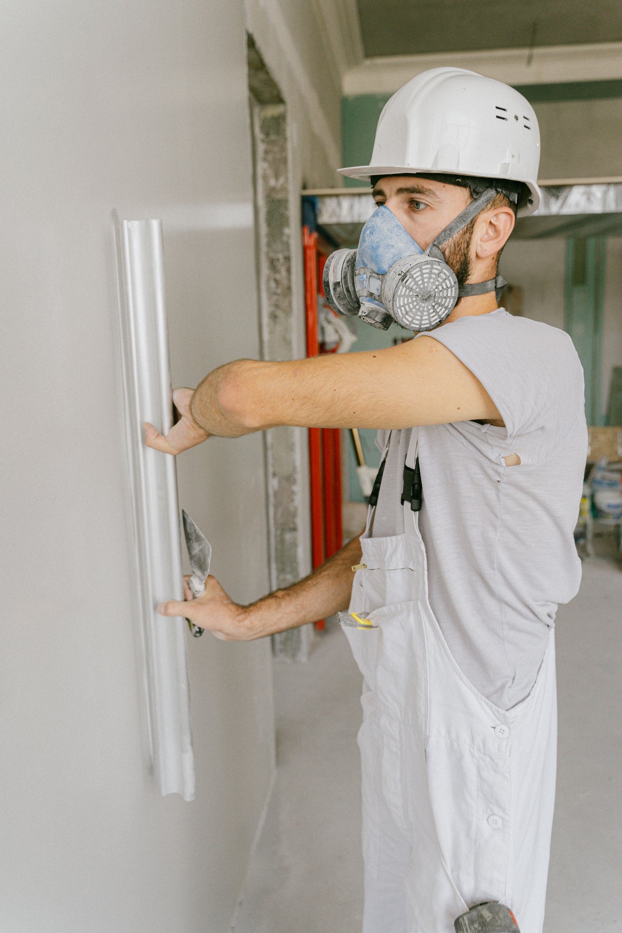 Construction worker smoothing a large section of wall with a wide blade knife