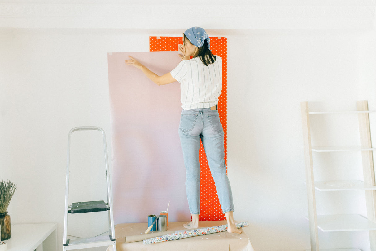 Person smoothing wallpaper onto a wall during hanging