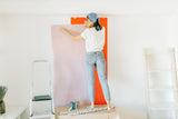 Person smoothing wallpaper onto a wall during hanging
