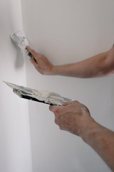 Decorator applying filler with a joint knife along a plasterboard seam