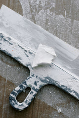 Close up of a filling knife blade covered in joint compound