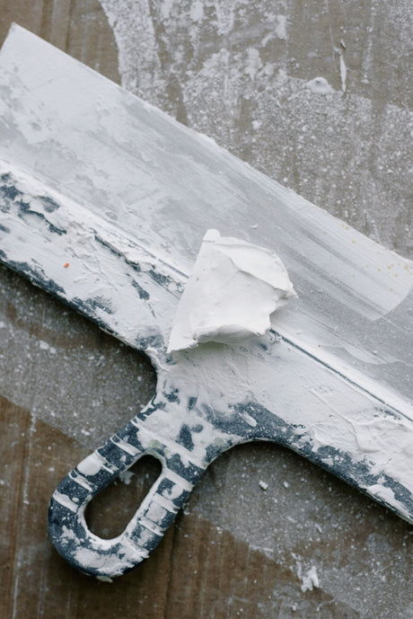 Close up of a filling knife blade covered in joint compound