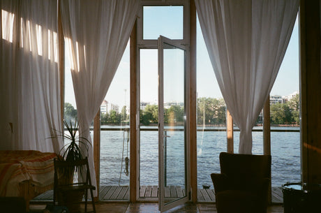 White-framed glass doors and windows with warm wood flooring in a cosy neutral room