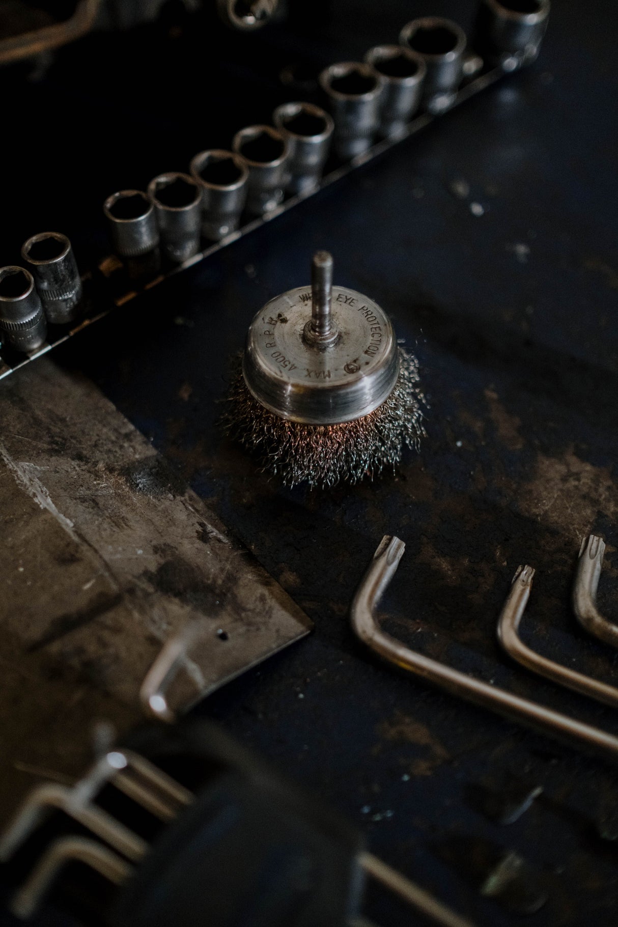 Close up of a wire brush with metal bristles on a workshop bench