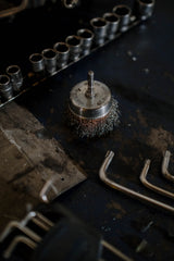 Close up of a wire brush with metal bristles on a workshop bench