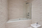Sleek modern bathroom with beige textured tiles and bathtub, complementing Dulux Egyptian Cotton