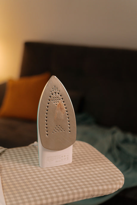 Iron resting on a fabric covered ironing board, illustrating the type of covered setup a Minky Smartfit felt pad underlay is designed to sit beneath