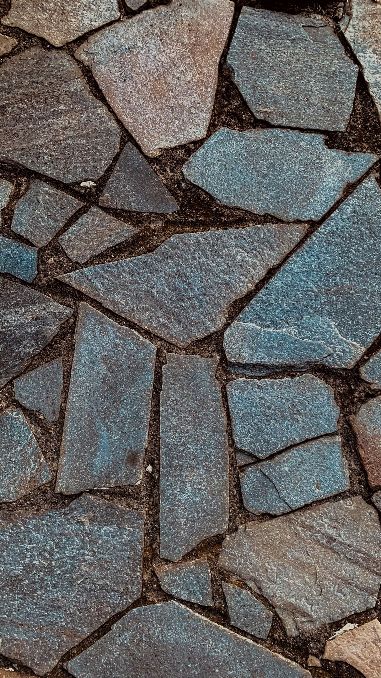 Warm toned brown and beige natural stone paving with jointed gaps between slabs