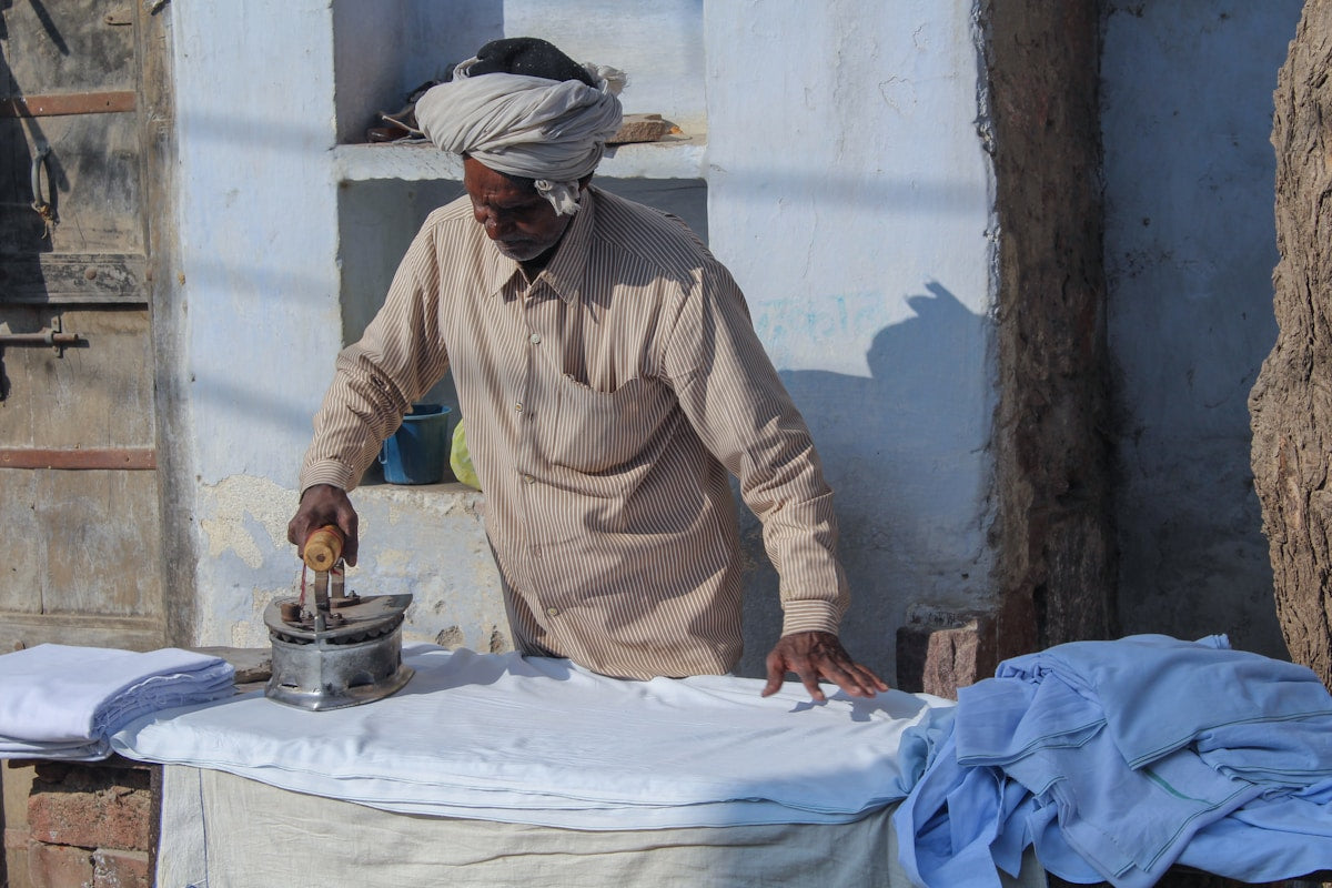 Person ironing clothes on an ironing board, demonstrating typical everyday use of a drawstring style ironing board cover
