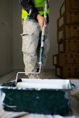 Decorator rolling paint onto a textured interior wall with a Purdy Colossus style roller sleeve