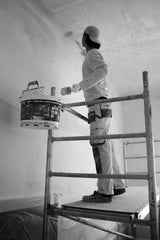Decorator rolling paint across a large wall area with a wide roller
