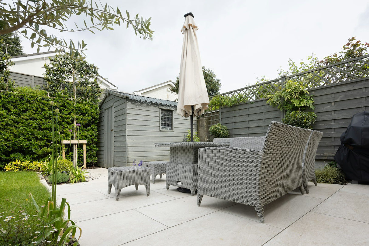 Traditional grey paving slab patio in a garden setting with outdoor furniture