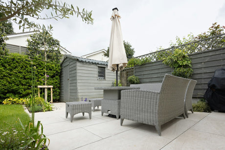 Traditional grey paving slab patio in a garden setting with outdoor furniture