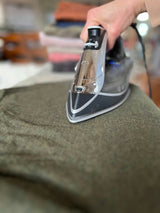 Person actively ironing a garment on an ironing board, demonstrating typical everyday use of an ironing board cover