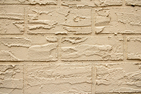 Close up of a textured beige brick masonry wall suited to the Purdy Colossus 18 inch 1/2 inch nap roller sleeve