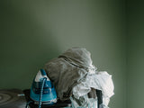 Iron and pile of clothes on an ironing board, showing the type of everyday ironing task suited to a large Minky ironing board cover