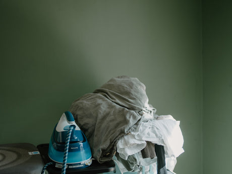 Iron and pile of clothes on an ironing board, showing the type of everyday ironing task suited to a large Minky ironing board cover