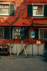 Painter using a long roller to cover a large exterior wall area, similar to work suited to the Purdy Colossus 12 inch sleeve