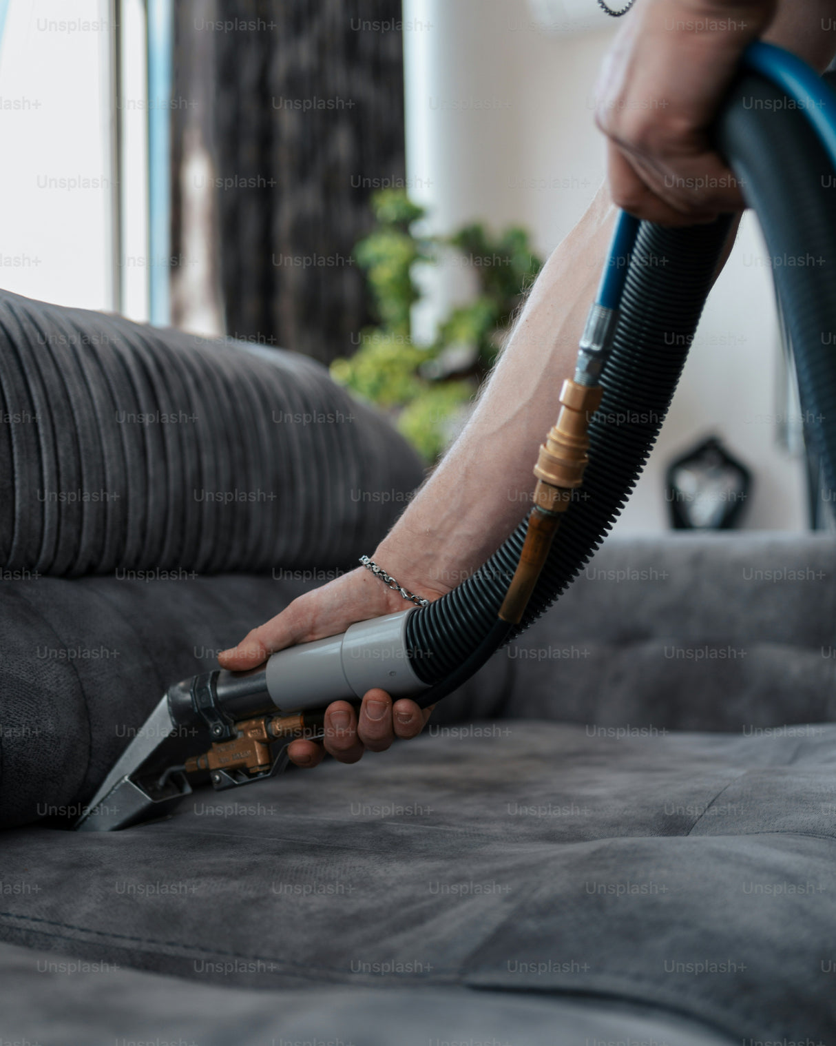 Hands cleaning and scrubbing fabric upholstery on a sofa