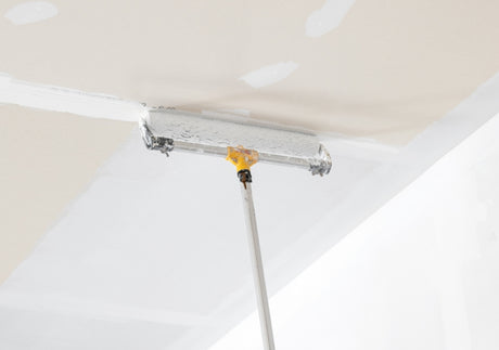 Decorator using a Purdy extension pole and roller frame to paint a ceiling